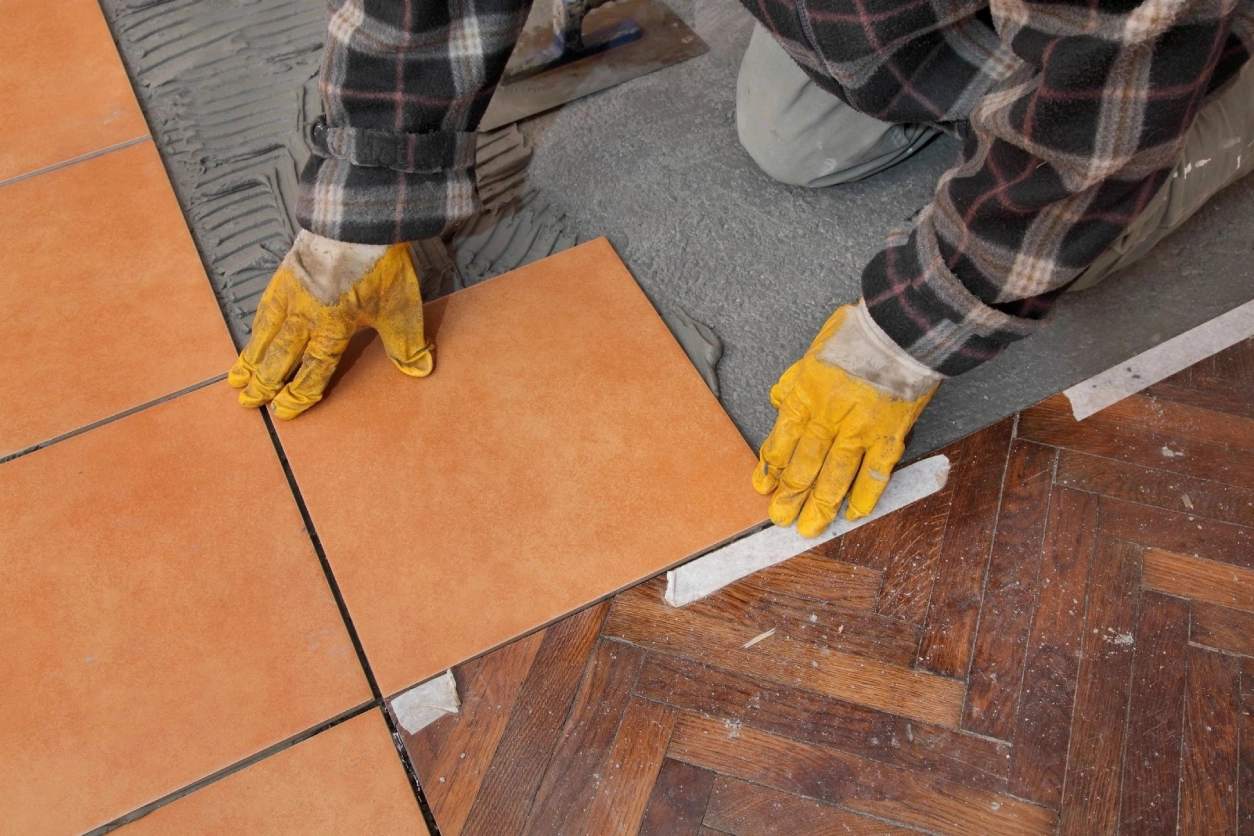 A person with yellow gloves on and holding onto tiles