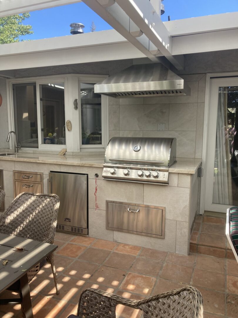 A grill and an outdoor kitchen with chairs